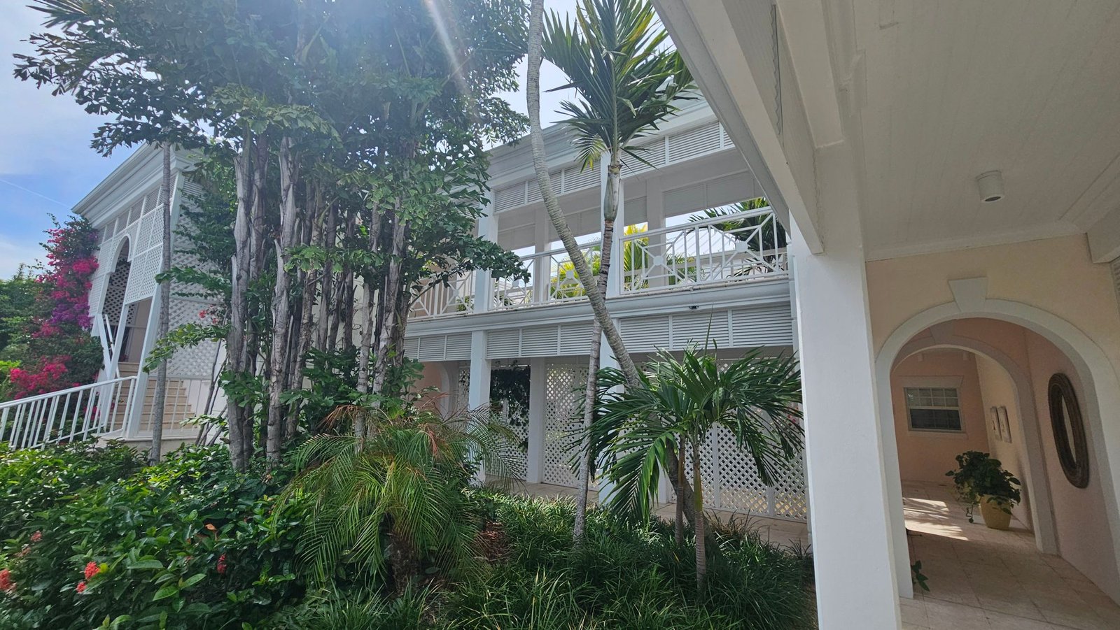 White colonial-style villa with lattice balconies and tropical garden