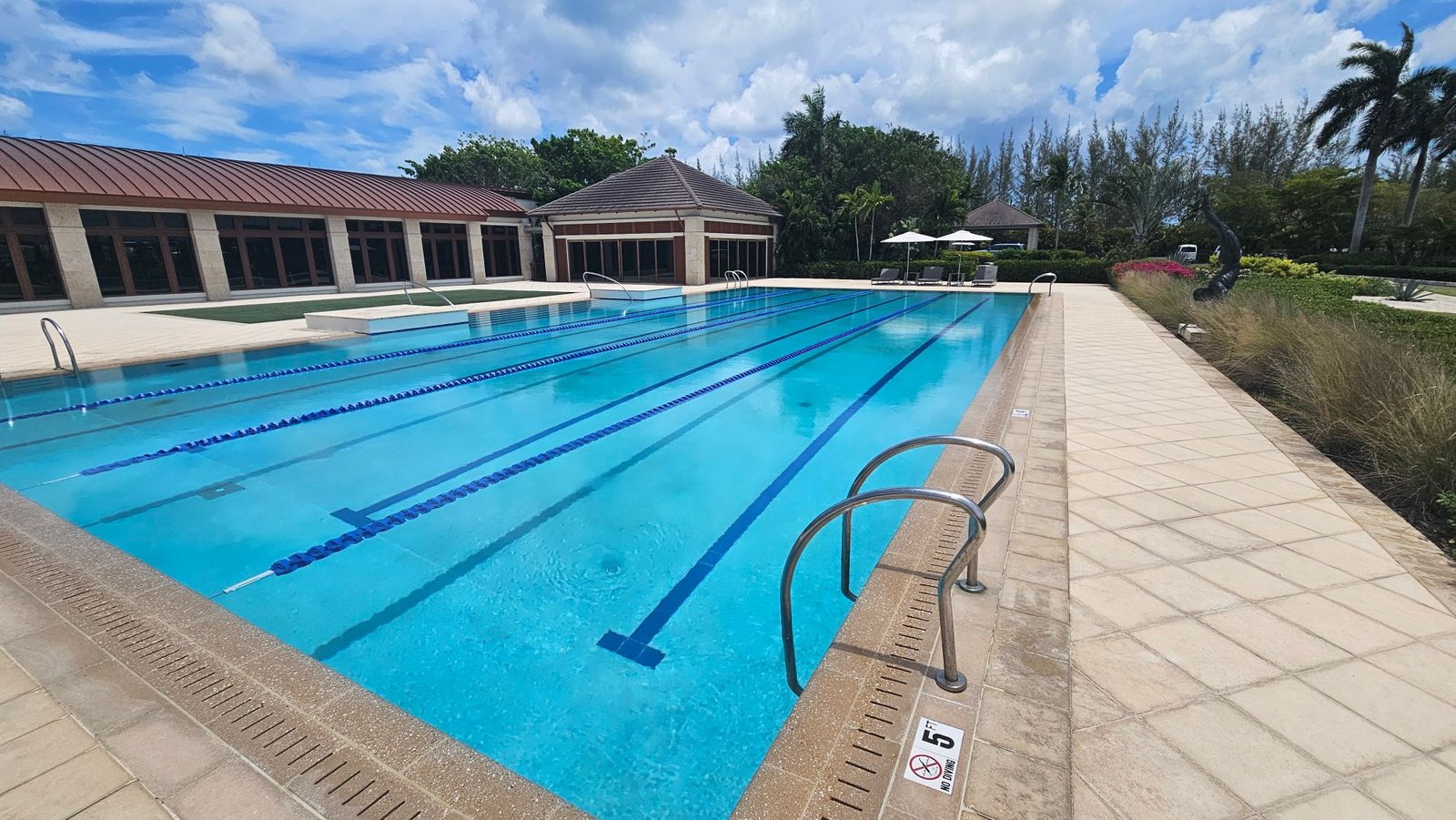Outdoor lap pool with lane lines beside a clubhouse