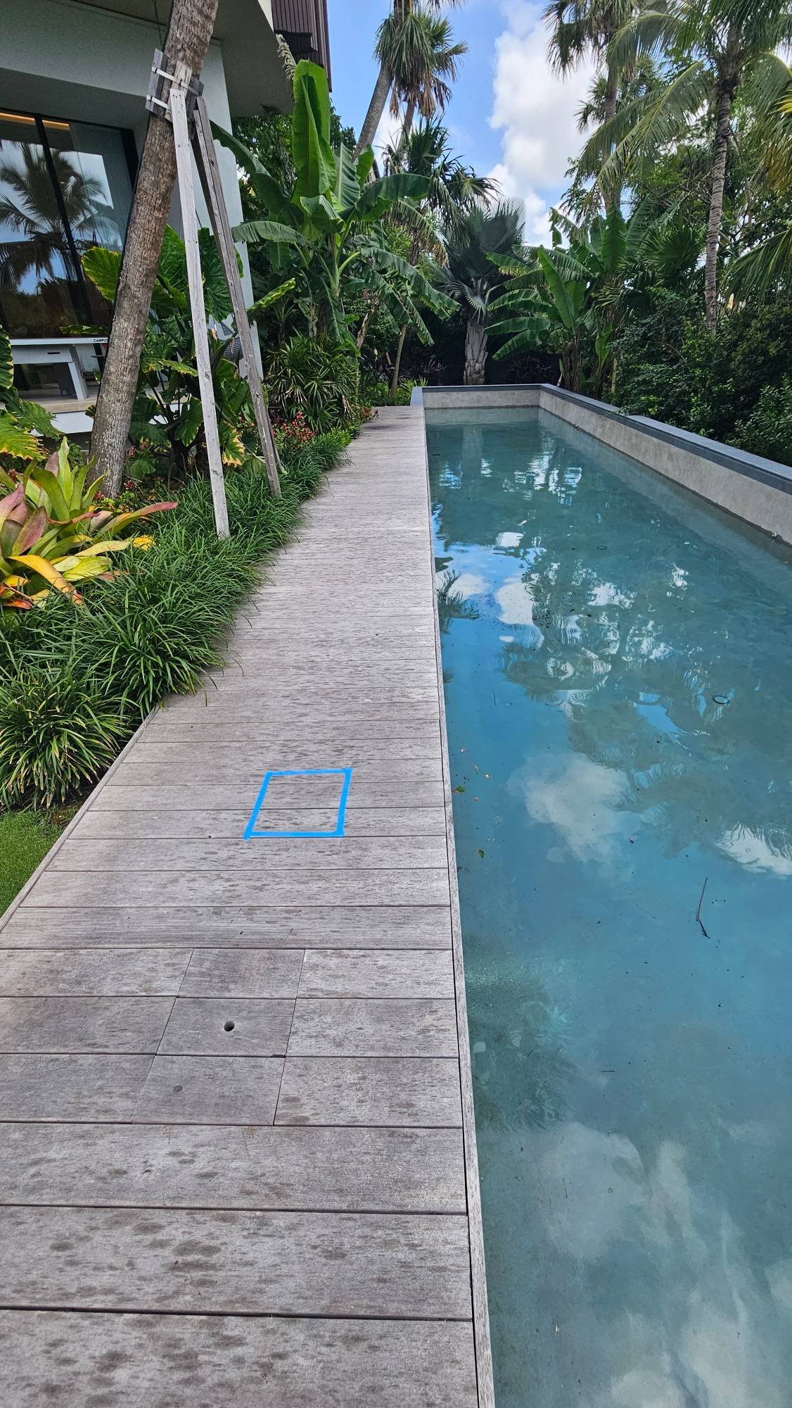 Wooden pool deck with the pinpointed leak location marked in blue tape