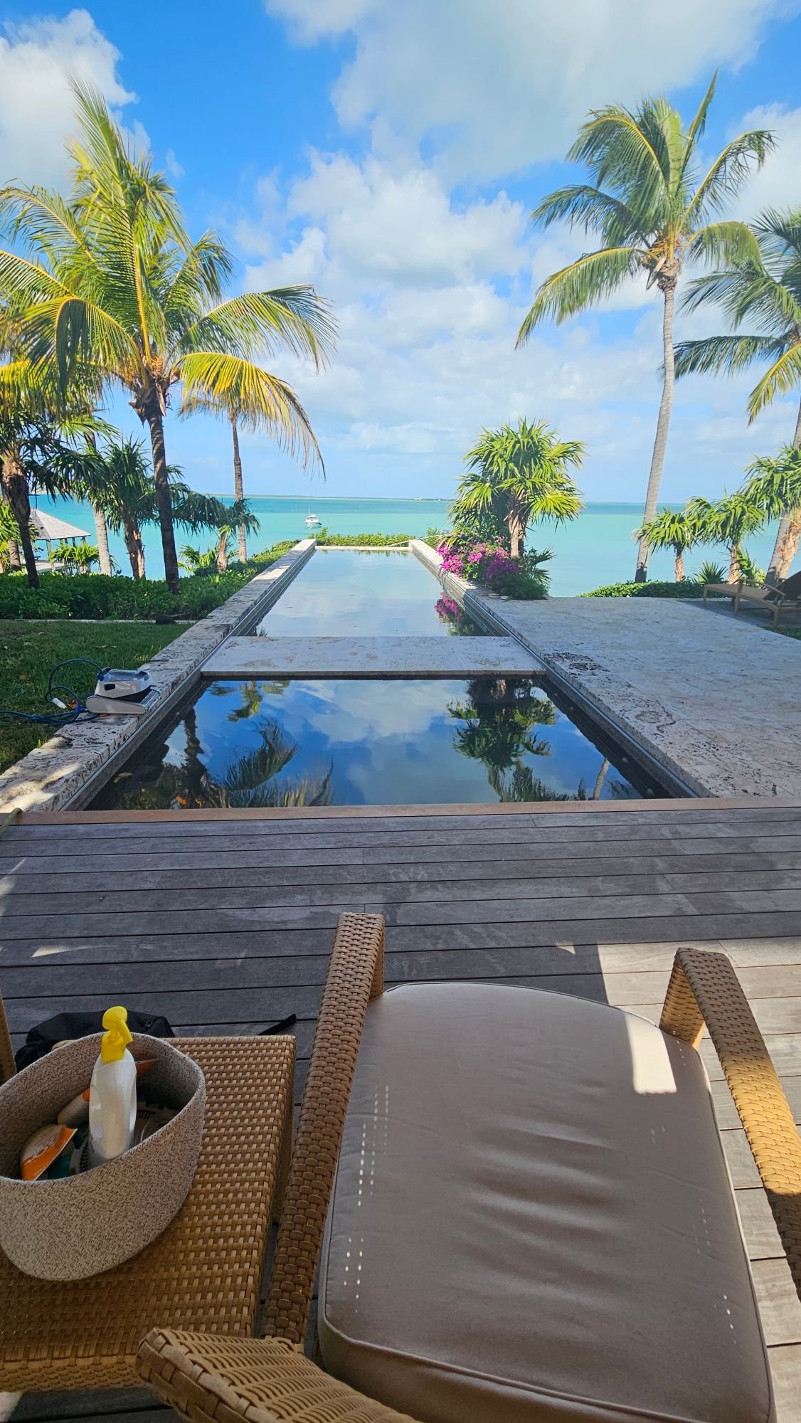 Long stone-edged pool leading to turquoise water and palm trees