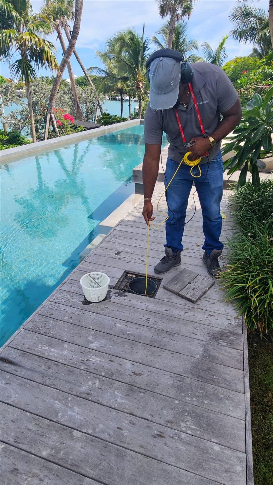 Technician listening for a leak with a headset and ground microphone beside a pool