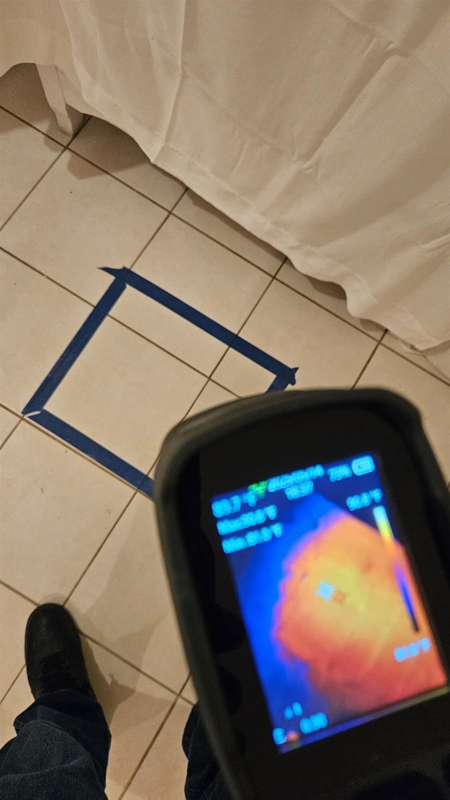 Thermal camera showing a hot spot under a floor area marked with blue tape